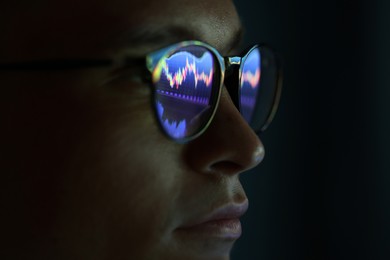 Photo of Young man wearing glasses with reflection on dark background, closeup