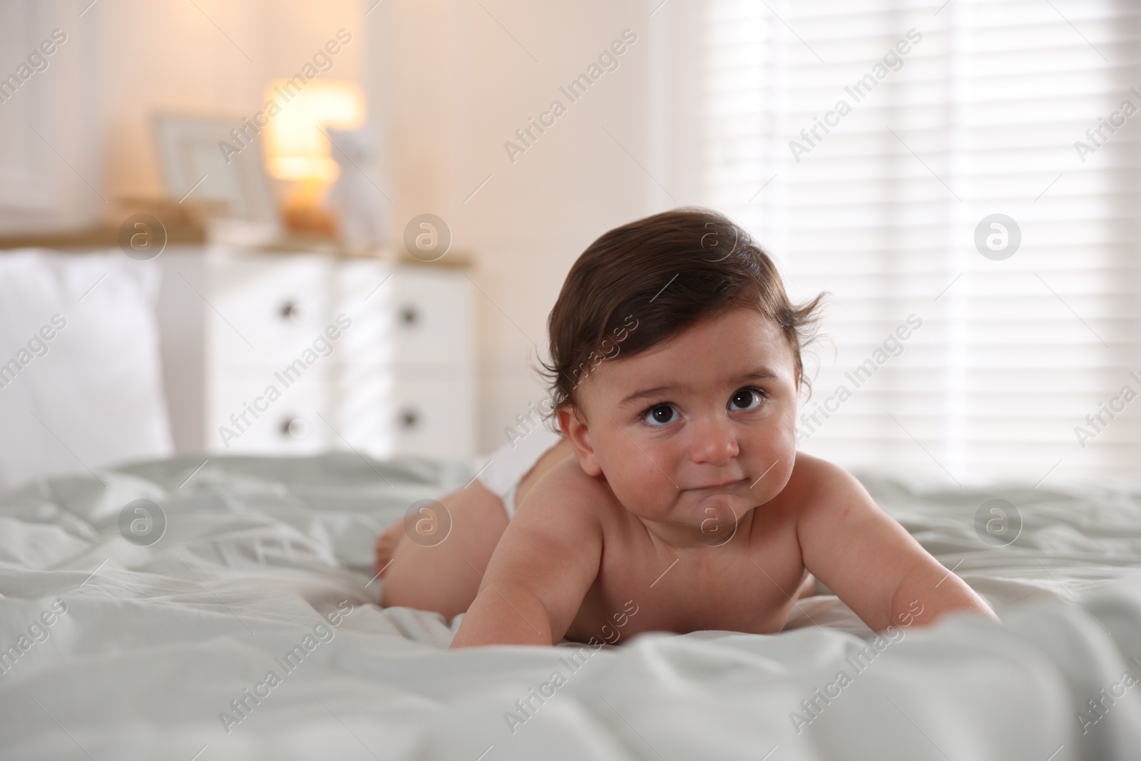 Photo of Cute little baby on bed at home, space for text