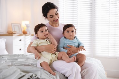 Photo of Happy mother with her cute little twin babies on bed indoors