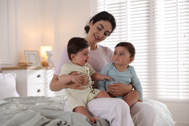 Photo of Happy mother with her cute little twin babies on bed indoors