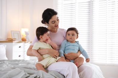 Photo of Happy mother with her cute little twin babies on bed indoors