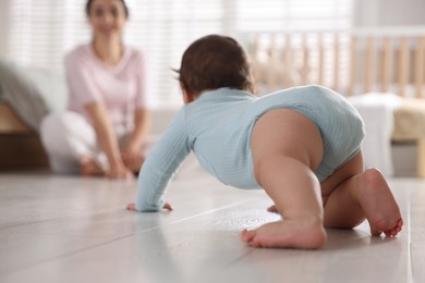 Photo of Mother with her cute little baby on floor indoors, selective focus