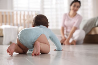 Photo of Mother with her cute little baby on floor indoors, selective focus