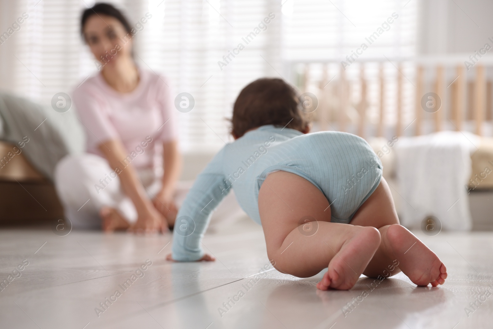 Photo of Mother with her cute little baby on floor indoors, selective focus