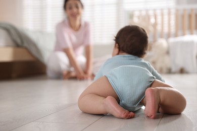 Photo of Mother with her cute little baby on floor indoors, selective focus