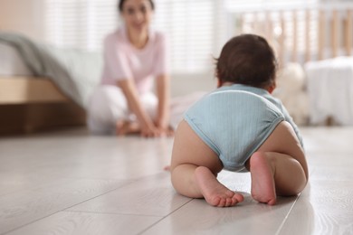 Photo of Mother with her cute little baby on floor indoors, selective focus