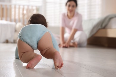 Photo of Mother with her cute little baby on floor indoors, selective focus
