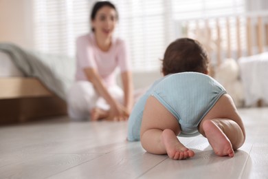 Photo of Mother with her cute little baby on floor indoors, selective focus