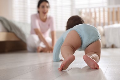 Photo of Mother with her cute little baby on floor indoors, selective focus