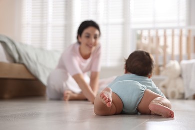 Photo of Mother with her cute little baby on floor indoors, selective focus