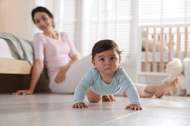 Photo of Mother with her cute little baby on floor indoors, selective focus