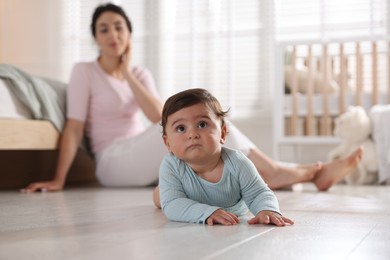 Photo of Mother with her cute little baby on floor indoors, selective focus