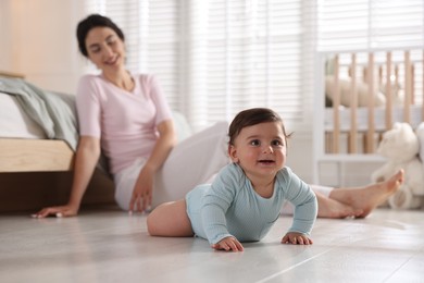 Photo of Mother with her cute little baby on floor indoors, selective focus