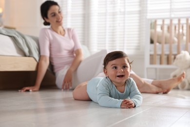 Photo of Mother with her cute little baby on floor indoors, selective focus
