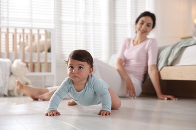 Photo of Mother with her cute little baby on floor indoors, selective focus