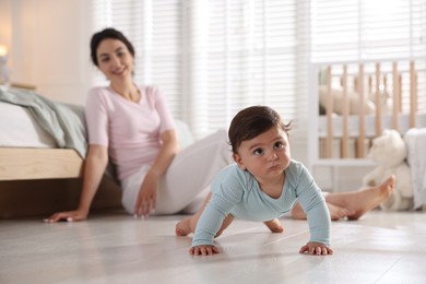 Photo of Mother with her cute little baby on floor indoors, selective focus
