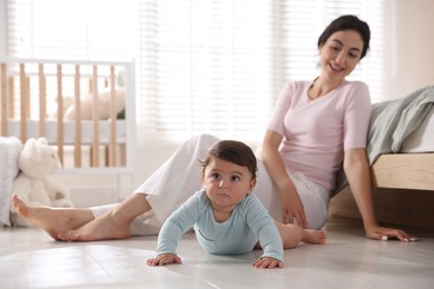 Photo of Mother with her cute little baby on floor indoors, selective focus