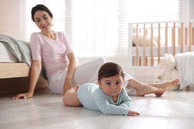 Photo of Mother with her cute little baby on floor indoors, selective focus