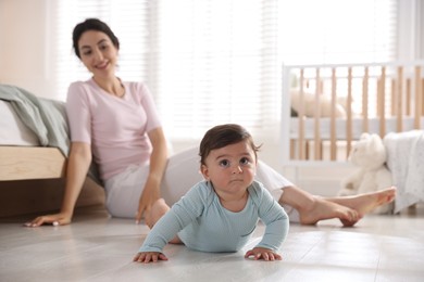 Photo of Mother with her cute little baby on floor indoors, selective focus