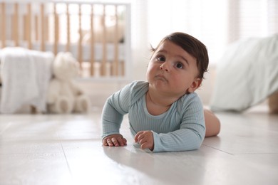Photo of Cute little baby lying on floor at home, space for text