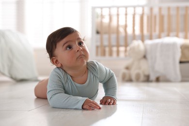 Photo of Cute little baby lying on floor at home, space for text