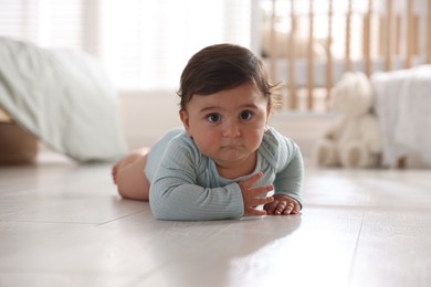 Photo of Cute little baby lying on floor at home
