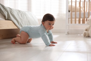 Photo of Cute little baby crawling on floor at home, space for text