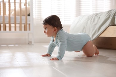 Photo of Cute little baby crawling on floor at home, space for text