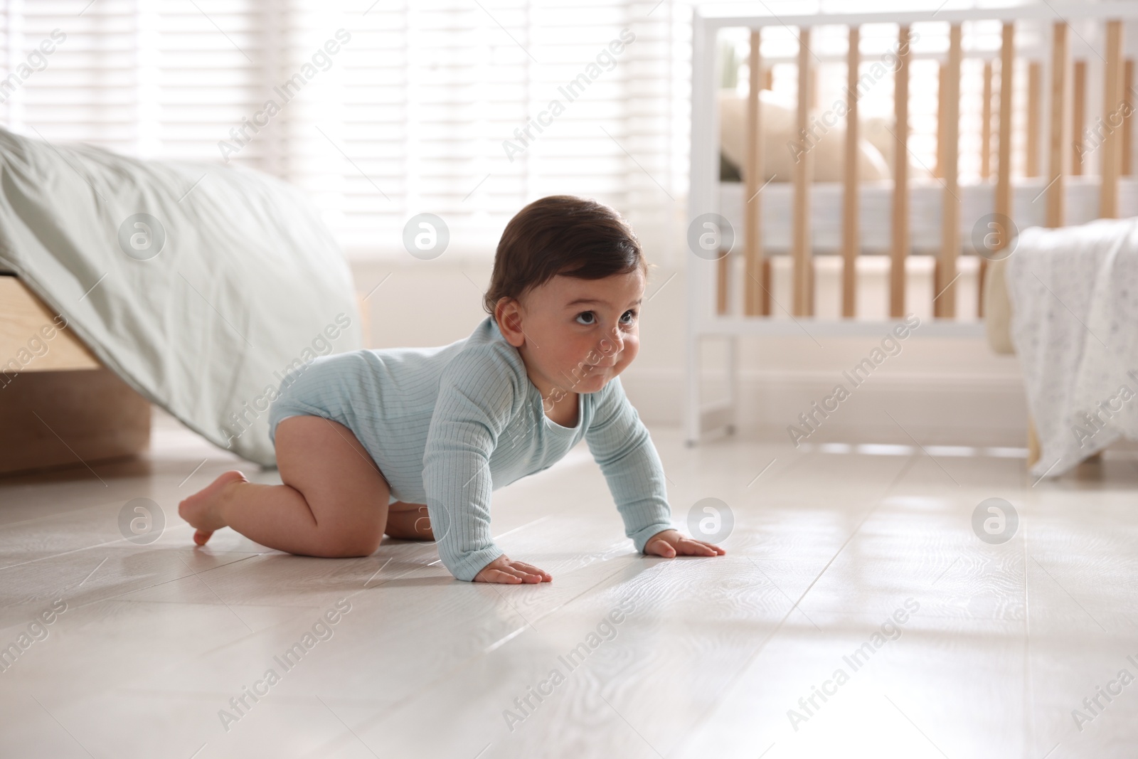 Photo of Cute little baby crawling on floor at home, space for text