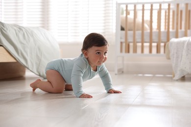 Photo of Cute little baby crawling on floor at home, space for text