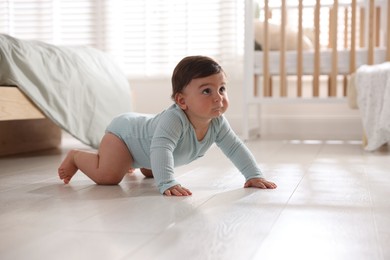 Photo of Cute little baby crawling on floor at home, space for text