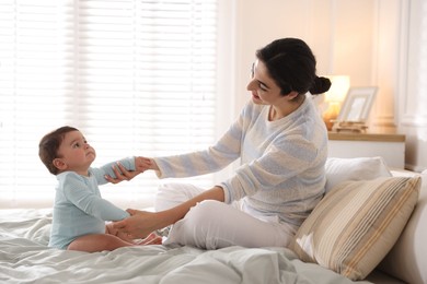 Photo of Mother with her cute little baby on bed indoors