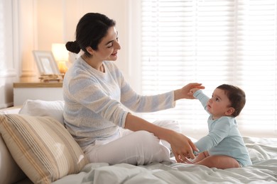 Photo of Mother with her cute little baby on bed indoors
