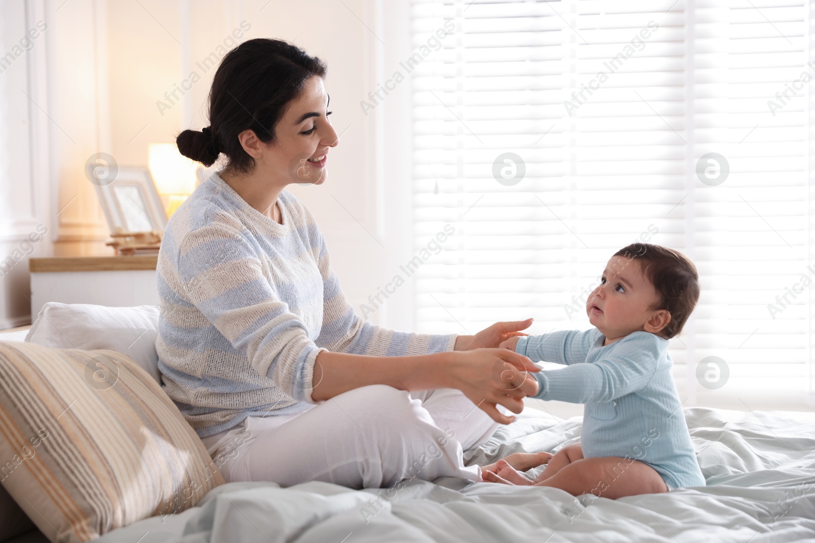 Photo of Mother with her cute little baby on bed indoors