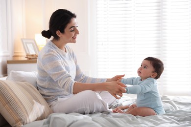 Photo of Mother with her cute little baby on bed indoors
