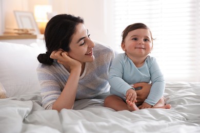 Photo of Mother with her cute little baby on bed indoors