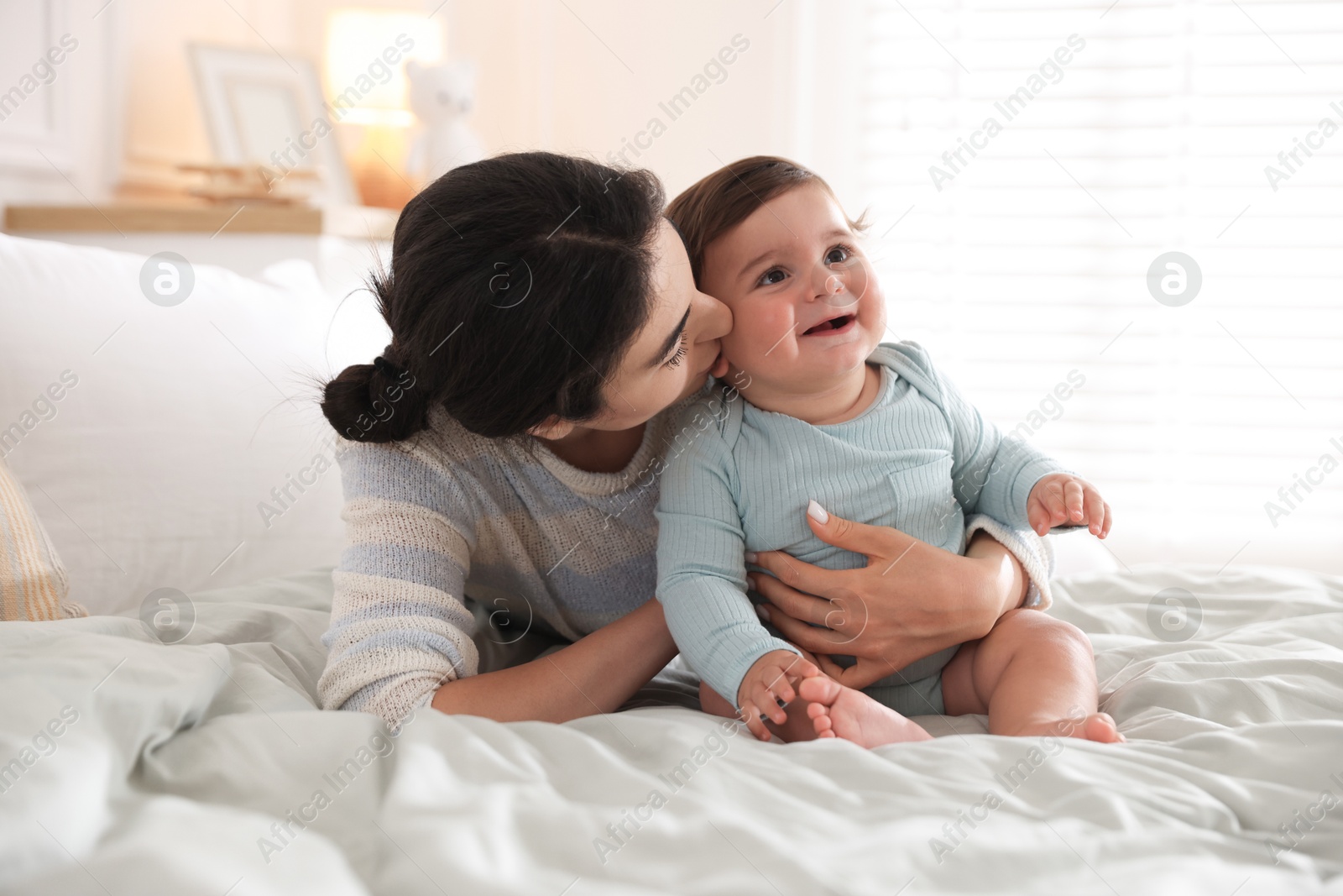 Photo of Mother with her cute little baby on bed indoors