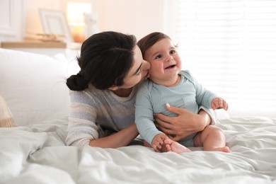 Photo of Mother with her cute little baby on bed indoors