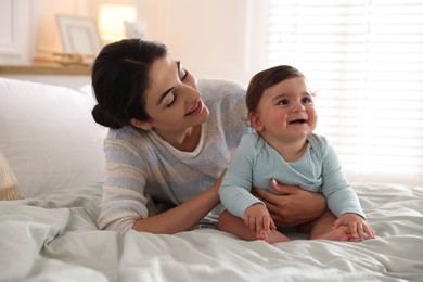 Photo of Mother with her cute little baby on bed indoors