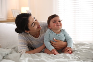 Photo of Mother with her cute little baby on bed indoors