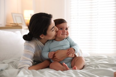 Photo of Mother with her cute little baby on bed indoors
