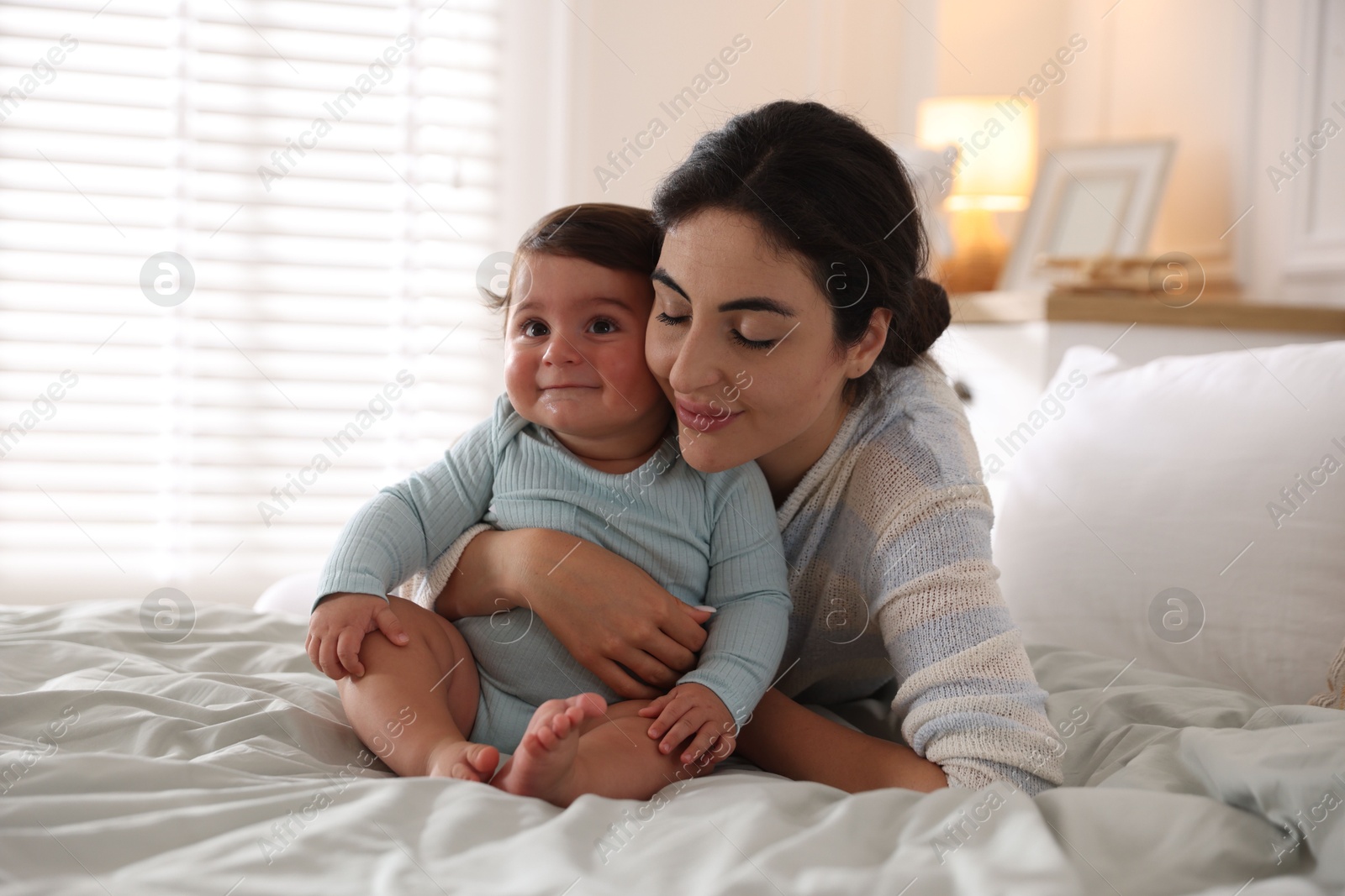 Photo of Mother with her cute little baby on bed indoors