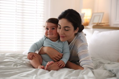 Photo of Mother with her cute little baby on bed indoors