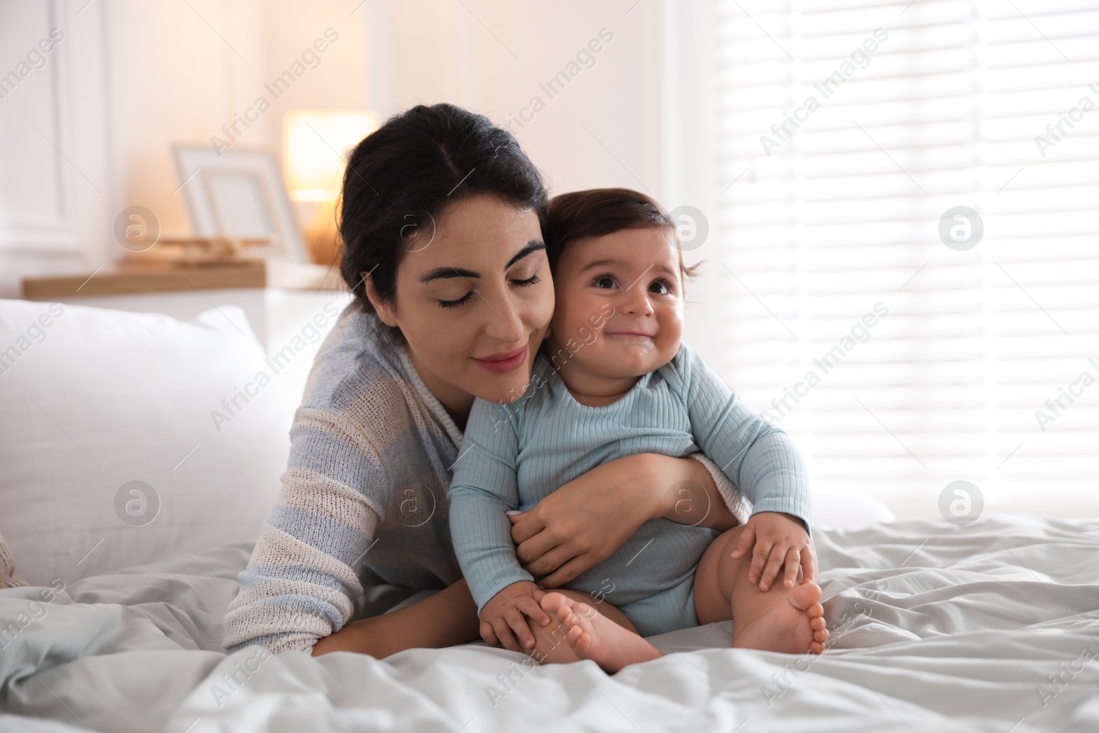 Photo of Mother with her cute little baby on bed indoors