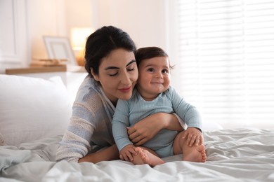 Photo of Mother with her cute little baby on bed indoors