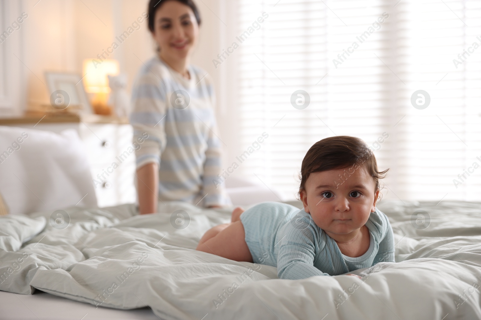 Photo of Mother with her cute little baby on bed indoors, selective focus