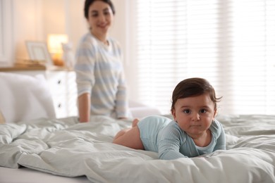Photo of Mother with her cute little baby on bed indoors, selective focus