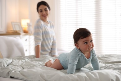 Photo of Mother with her cute little baby on bed indoors, selective focus