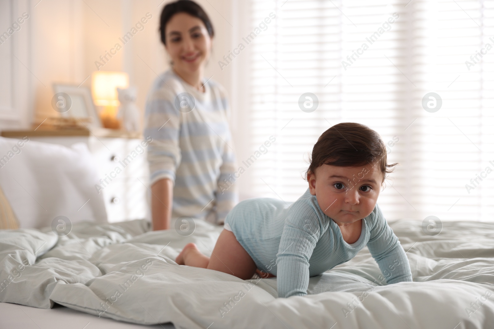 Photo of Mother with her cute little baby on bed indoors, selective focus