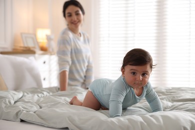 Photo of Mother with her cute little baby on bed indoors, selective focus